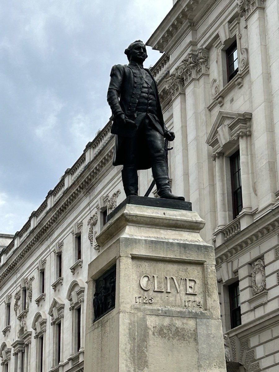 Bronze statue of Robert Clive on a high stone pedestal inscribed CLIVE 1725 1774, against the white Portland-stone facade of the Foreign and Commonwealth Office building, King Charles Street, London.